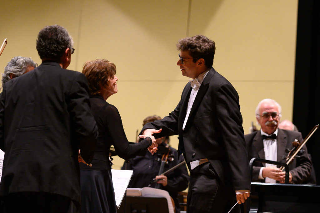 Dr. Geoffrey Pope shakes hands with Concertmaster, Rebecca Rutkowski